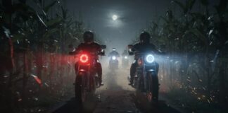 Motorcyclists riding through a cornfield at night under a full moon
