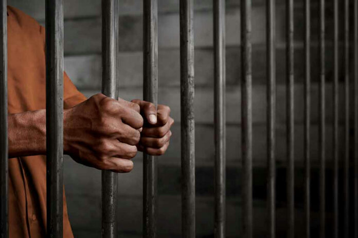 772489252 Hands gripping prison cell bars tightly.