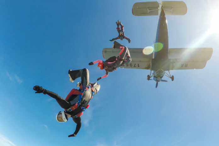 shutterstock2464720745 Skydivers freefalling below a small aircraft blue sky