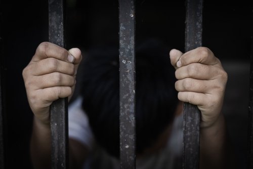 The,Child,Captured,The,Iron,Cage,With,Sadness,And,Despair. A pair of hands gripping metal bars, suggesting confinement