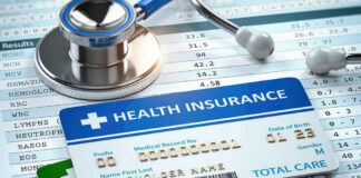 Stethoscope and health insurance cards on medical chart.