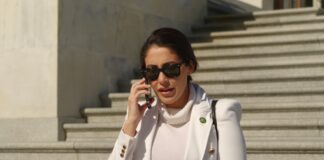 Woman in white coat talking on a phone on stone steps