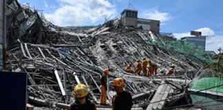 People walk through a street of destroyed buildings and rubble