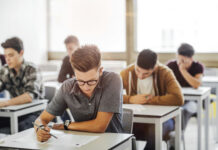 Graduation Trap: DEI Box Or No Diploma? Students taking a test in a classroom.