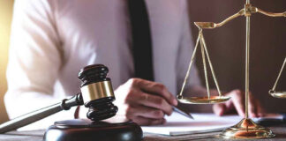 Gavel and scales beside a person writing.
