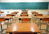 Empty classroom with wooden desks and chalkboard.