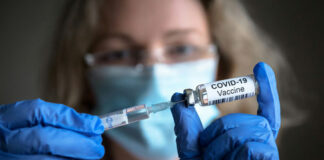 Person holding COVID-19 vaccine vial and syringe.