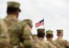 Troop Injury Numbers Continue Rising U.S. flag flying above a formation of soldiers in uniform
