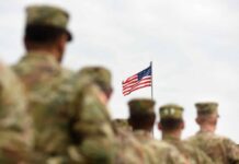 Troop Injury Numbers Continue Rising U.S. flag flying above a formation of soldiers in uniform