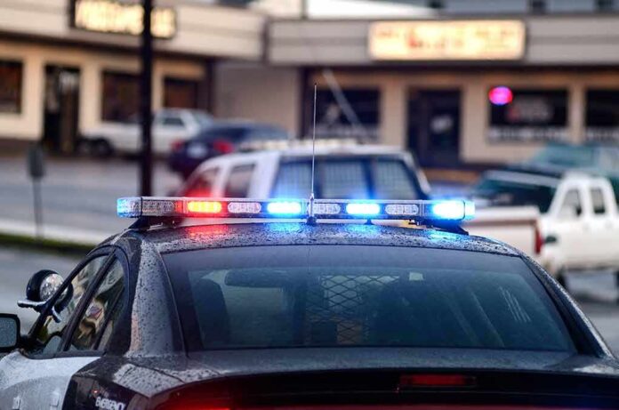 shutterstock_123247678 Police car with flashing red and blue lights in a parking lot