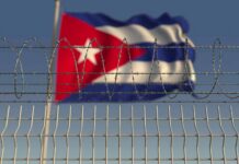 Cuba Playbook Targets U.S. Bases Barbed wire fence with Cuban flag in the background