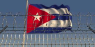 Barbed wire fence with Cuban flag in the background