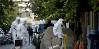 forensic investigators in white protective suits walking on a city street