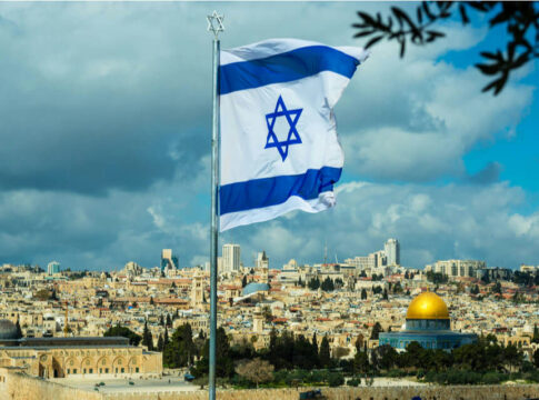 Israeli flag waving in front of the Jerusalem skyline with a golden dome in view