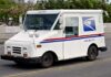 USPS delivery truck driving on urban street.