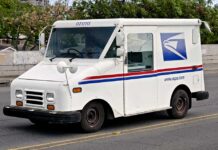 USPS delivery truck driving on urban street.