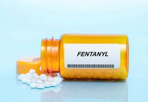 Orange pill bottle labeled Fentanyl with white pills.