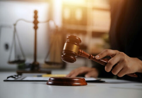 Judge's hand striking a wooden gavel on a sound block