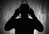 Silhouette of person holding a noose overhead.