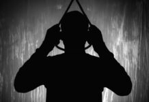 Silhouette of person holding a noose overhead.