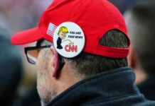 Person wearing a pin with Donald Trump and CNN logo.