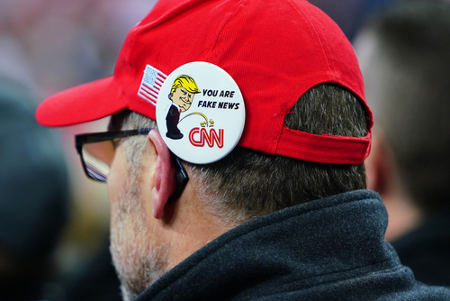 Person wearing a pin with Donald Trump and CNN logo.