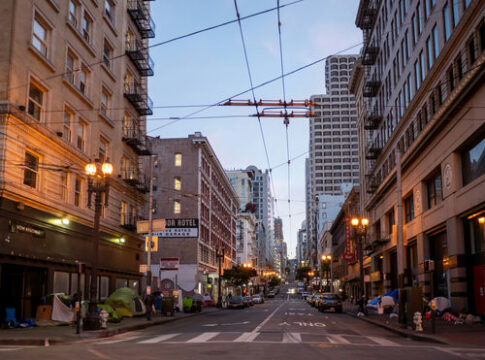 City street with tall buildings and tents along sidewalks