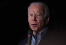 Man with silver hair speaking into a microphone.