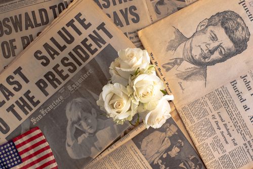 Newspapers, roses, and American flag mourning John F. Kennedy.