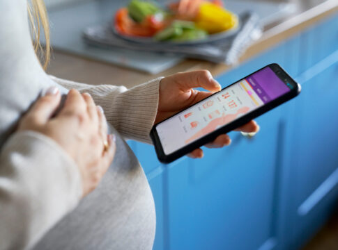 Pregnant woman checking a pregnancy app on a smartphone