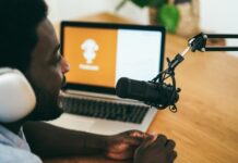 Person recording podcast with laptop and microphone.