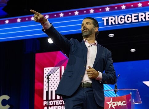 A man giving a speech at a conference, gesturing emphatically