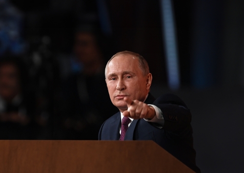 Man in suit pointing during a speech.