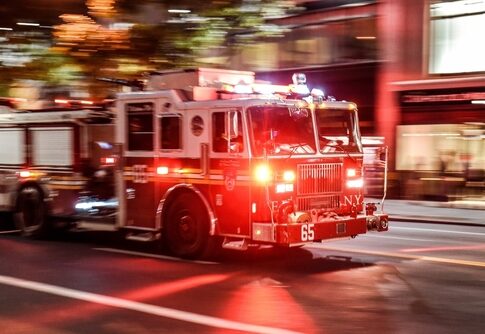 A fire truck with flashing lights responding to an emergency in a city at night