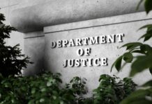 Department of Justice sign surrounded by greenery.