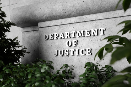 Department of Justice sign surrounded by greenery.