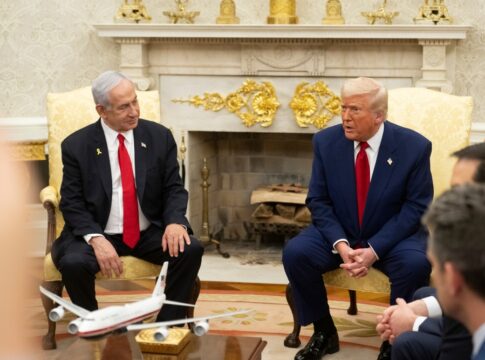 Two suited men seated in a formal meeting room