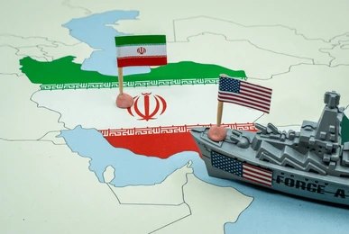 Map of Iran with Iranian and U.S. flags and a toy warship nearby