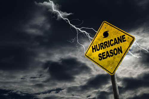 Hurricane season warning sign with lightning in stormy sky.